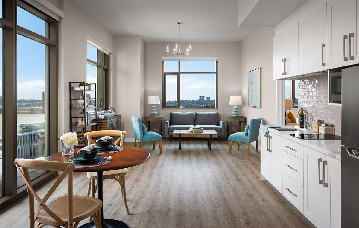 A modern apartment interior featuring a bright living room with stylish furniture, an open kitchen, and a small dining area.