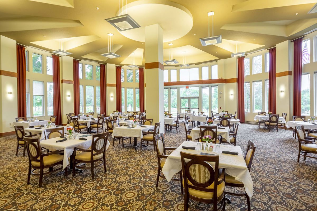 An elegant dining room with neatly arranged tables and chairs, featuring large windows and pleasant decor.