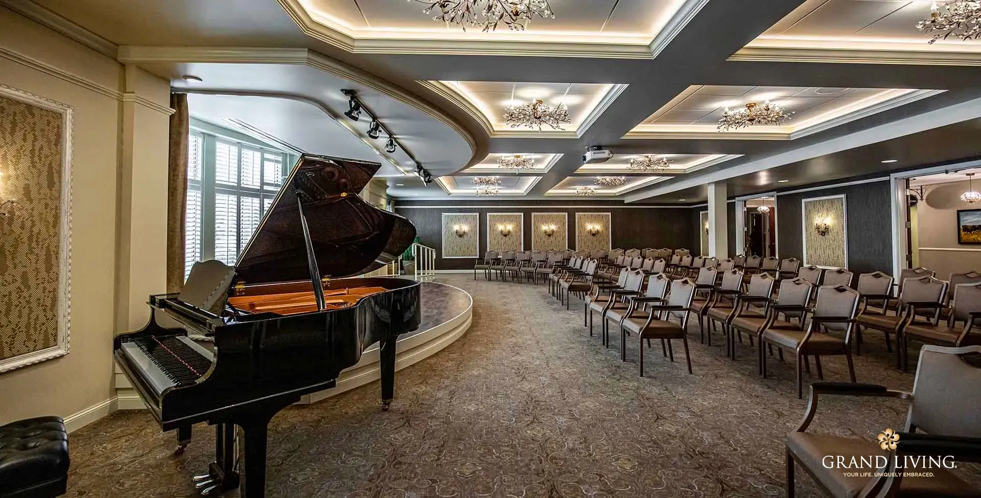 An elegant concert hall with a grand piano on stage and rows of empty chairs.