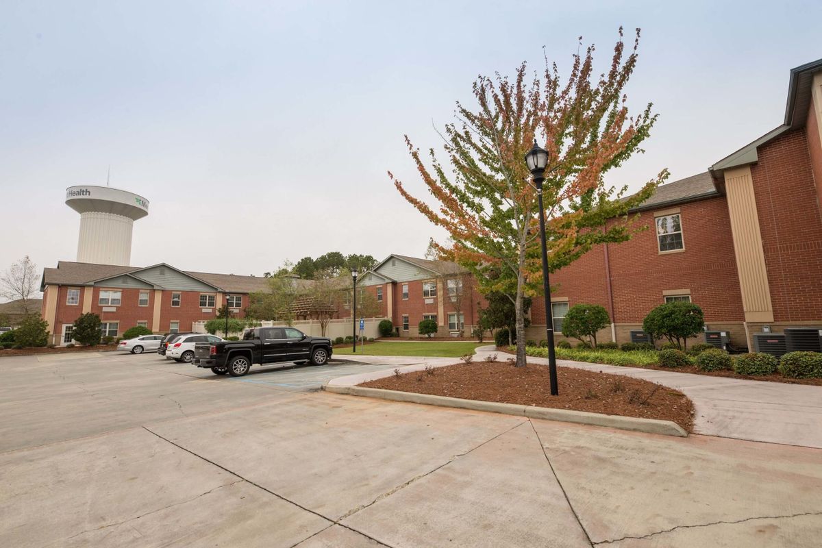 A residential parking lot with apartment buildings and trees.