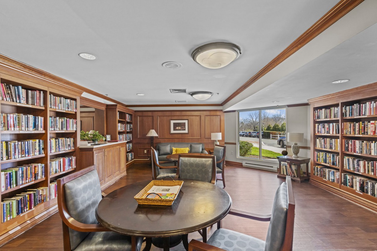 A cozy library reading area with wood paneling, bookshelves, and comfortable seating.