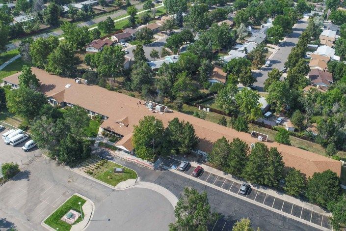 Aerial view of a suburban residential area with houses, trees, and a parking lot.