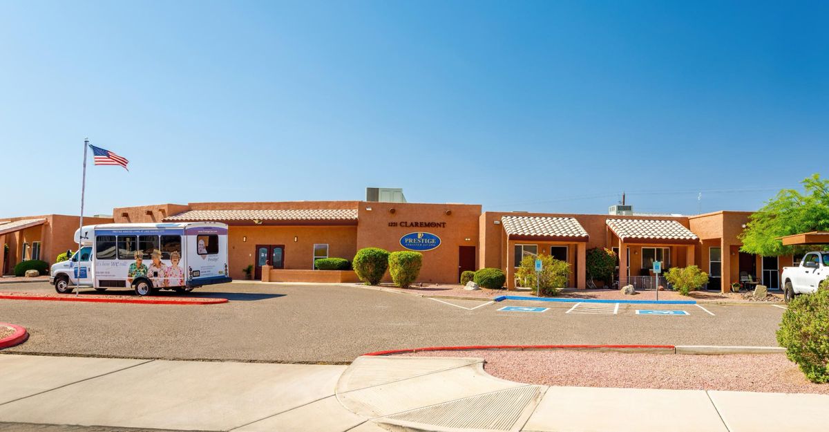 A medical facility with a desert-themed exterior and an adjacent parking lot under a clear blue sky.