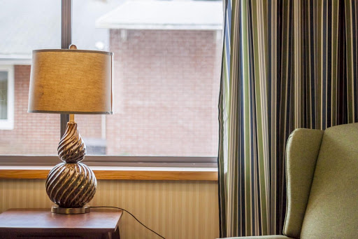 A cozy corner of a room featuring a stylish lamp and striped curtains by the window.