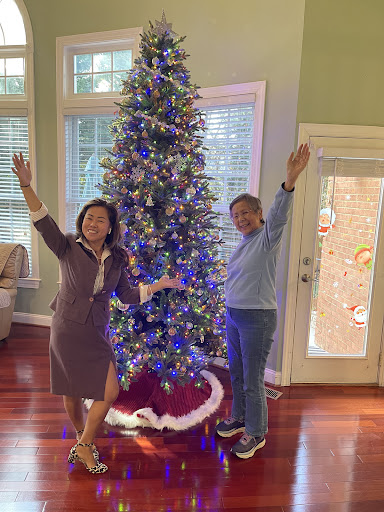 Two people joyfully celebrating the festive season beside a beautifully decorated Christmas tree.