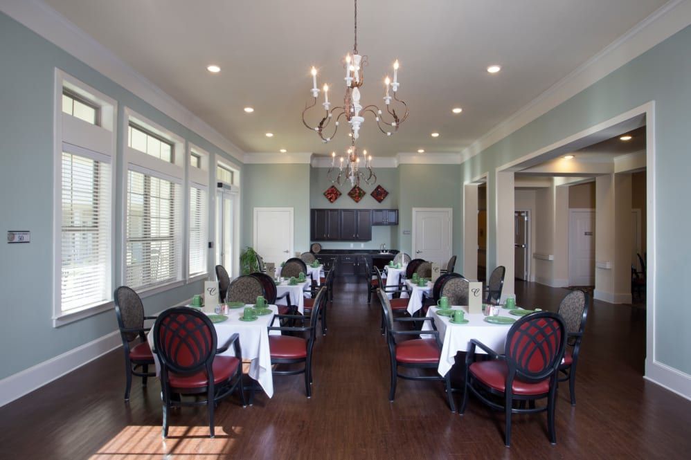 An elegant dining room with neatly arranged tables and chairs under a chandelier.