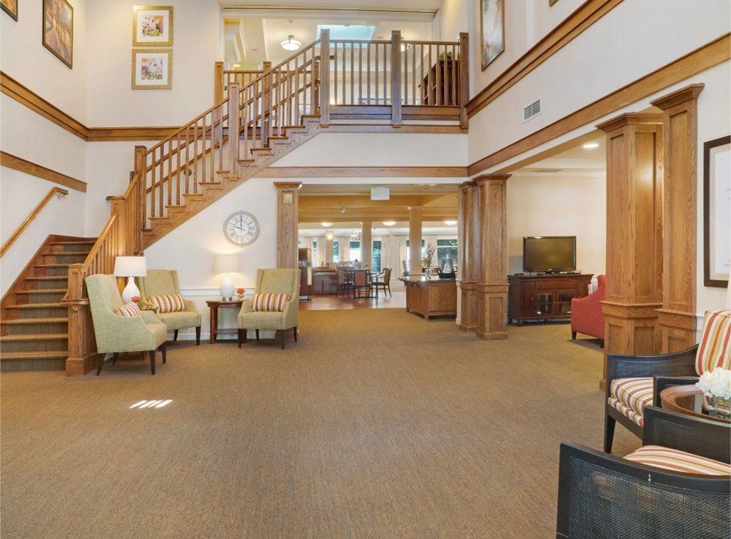 A spacious hotel lobby with comfortable seating and a wooden staircase.