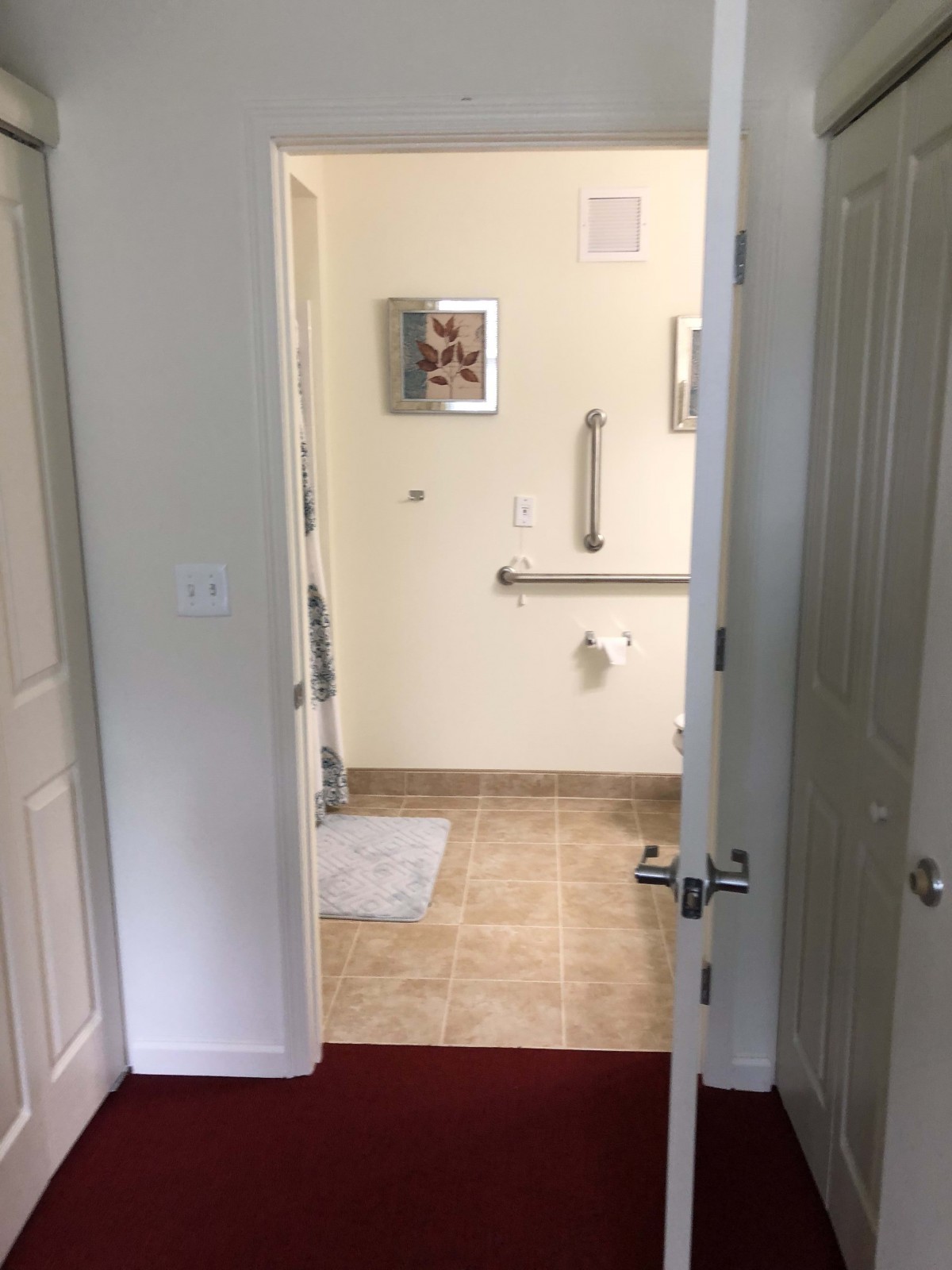 View of a bathroom through an open doorway with tile flooring and safety features.