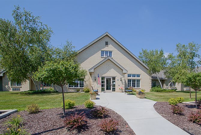 A charming residential house with a neatly landscaped front yard and a paved pathway leading to the entrance.