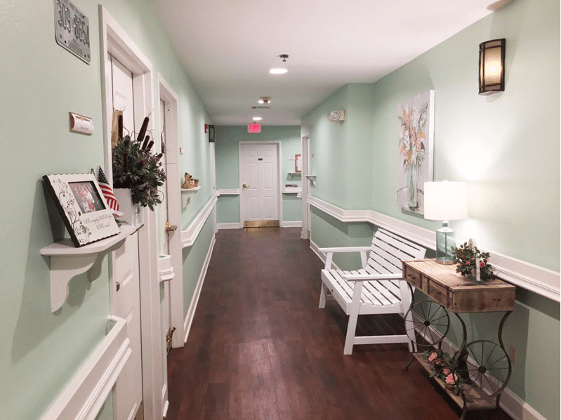 A cozy hallway with mint green walls, a white bench, and decorative artwork.