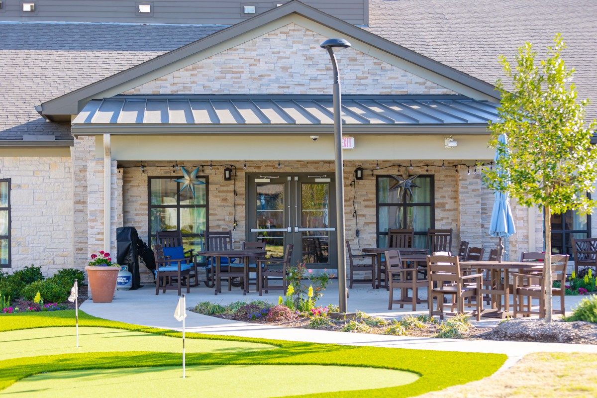 A cozy patio area with outdoor seating and a small putting green in front of a building.