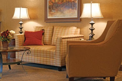 A cozy living room with a checkered sofa, armchair, and warm lighting.