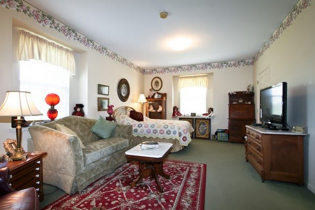 A traditionally decorated bedroom featuring a bed, sofa, and ornate carpet.