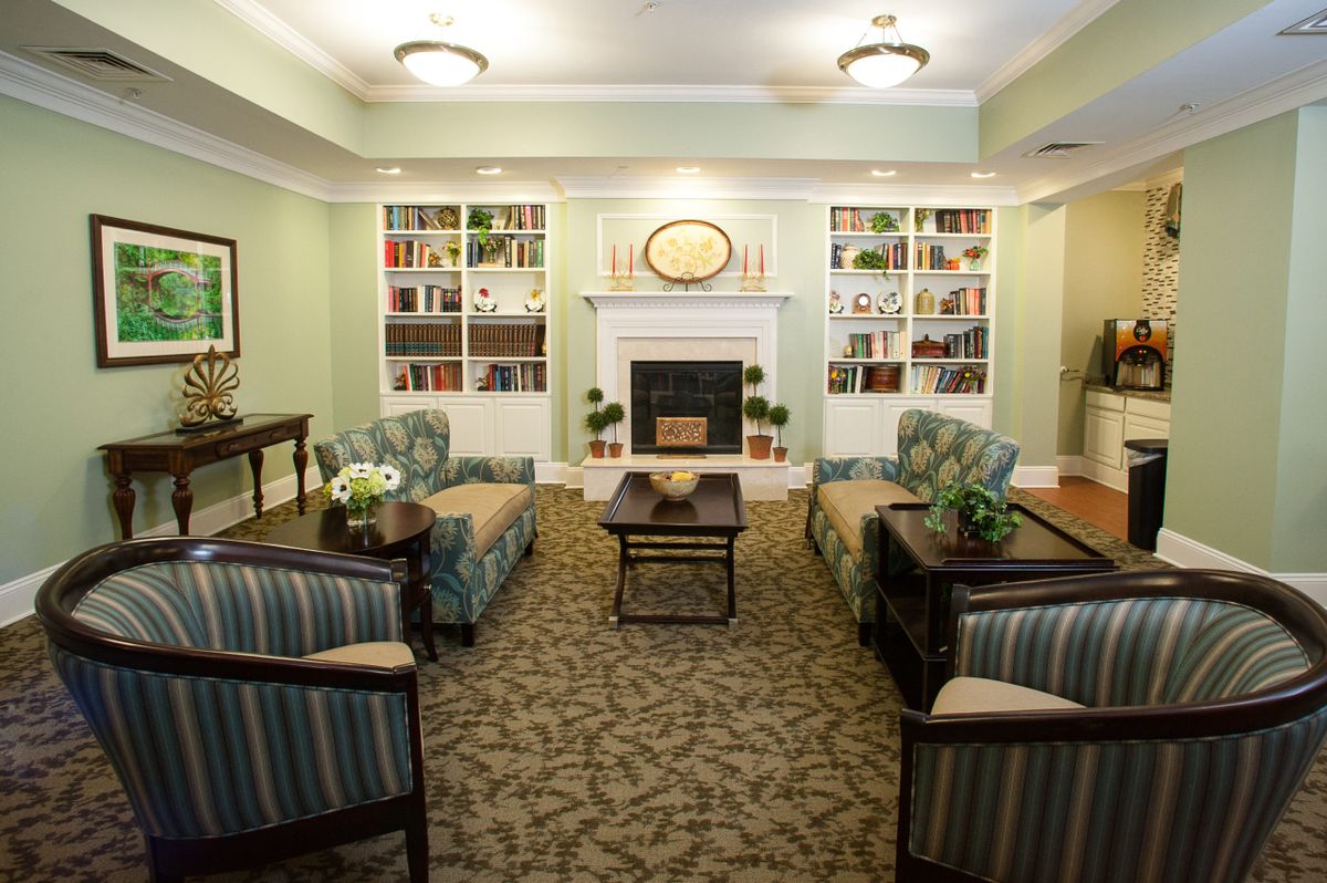 A cozy living room with a fireplace, surrounded by comfortable seating and bookshelves.