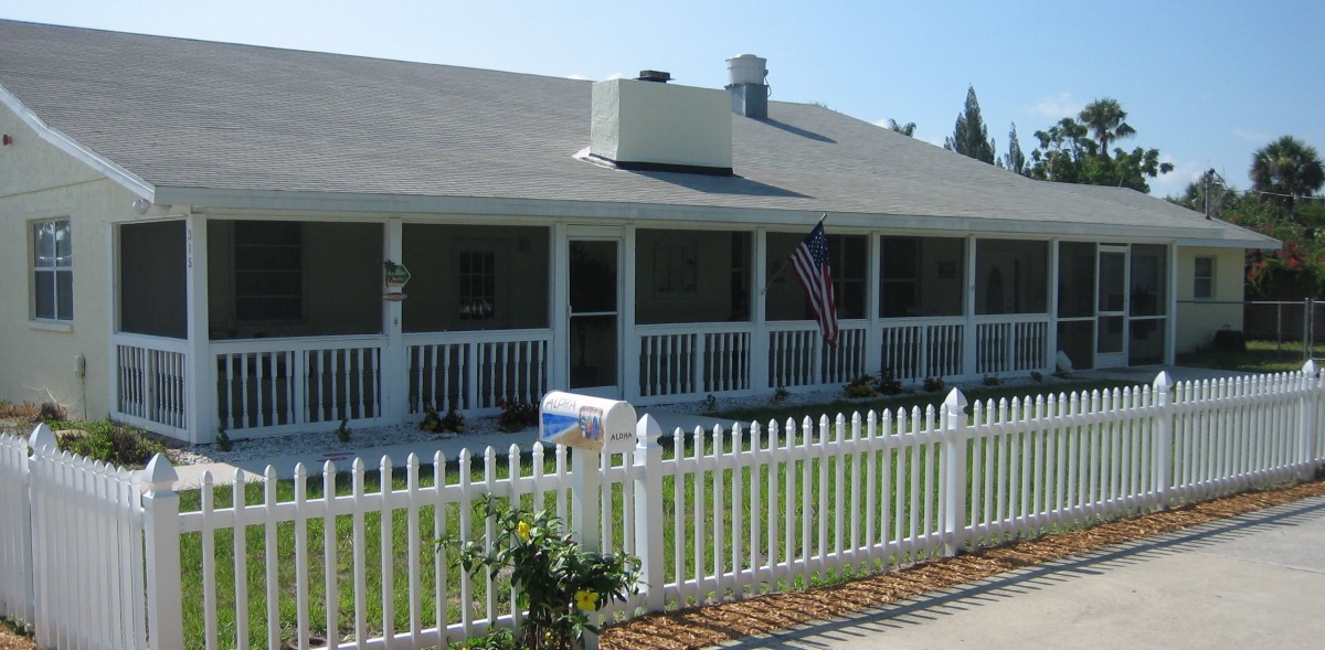 A charming house with a white picket fence and an American flag on the porch.