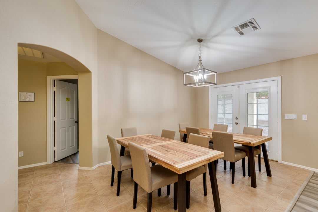 A modern dining room featuring a large wooden table with upholstered chairs and a stylish chandelier.