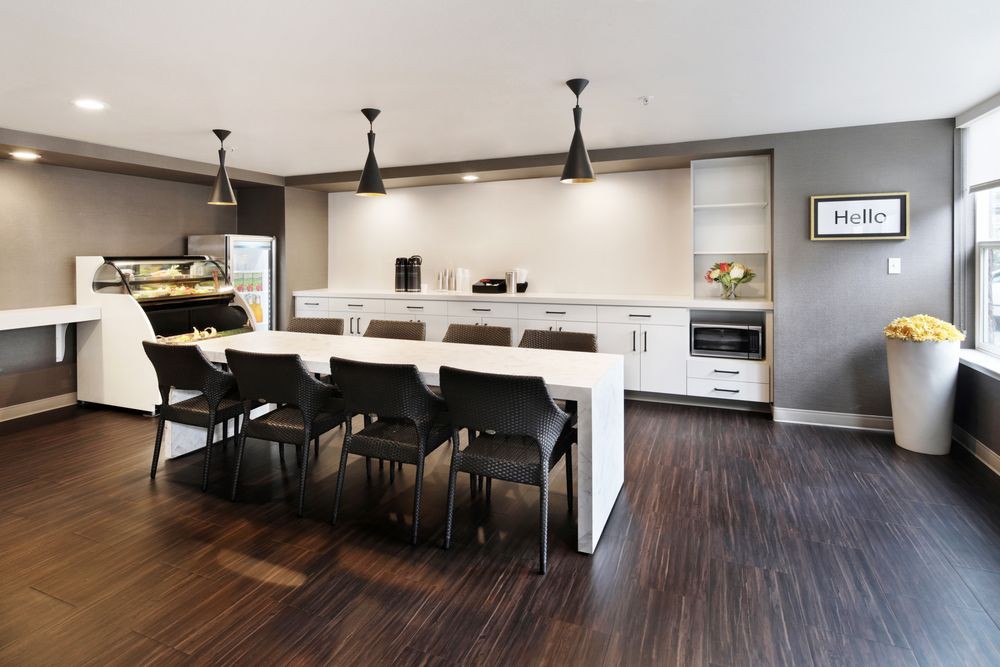A modern kitchen with sleek white countertops, bar stools, and pendant lighting.