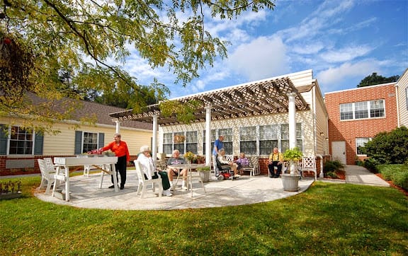 A group of people enjoying a sunny day on a patio with a pergola.