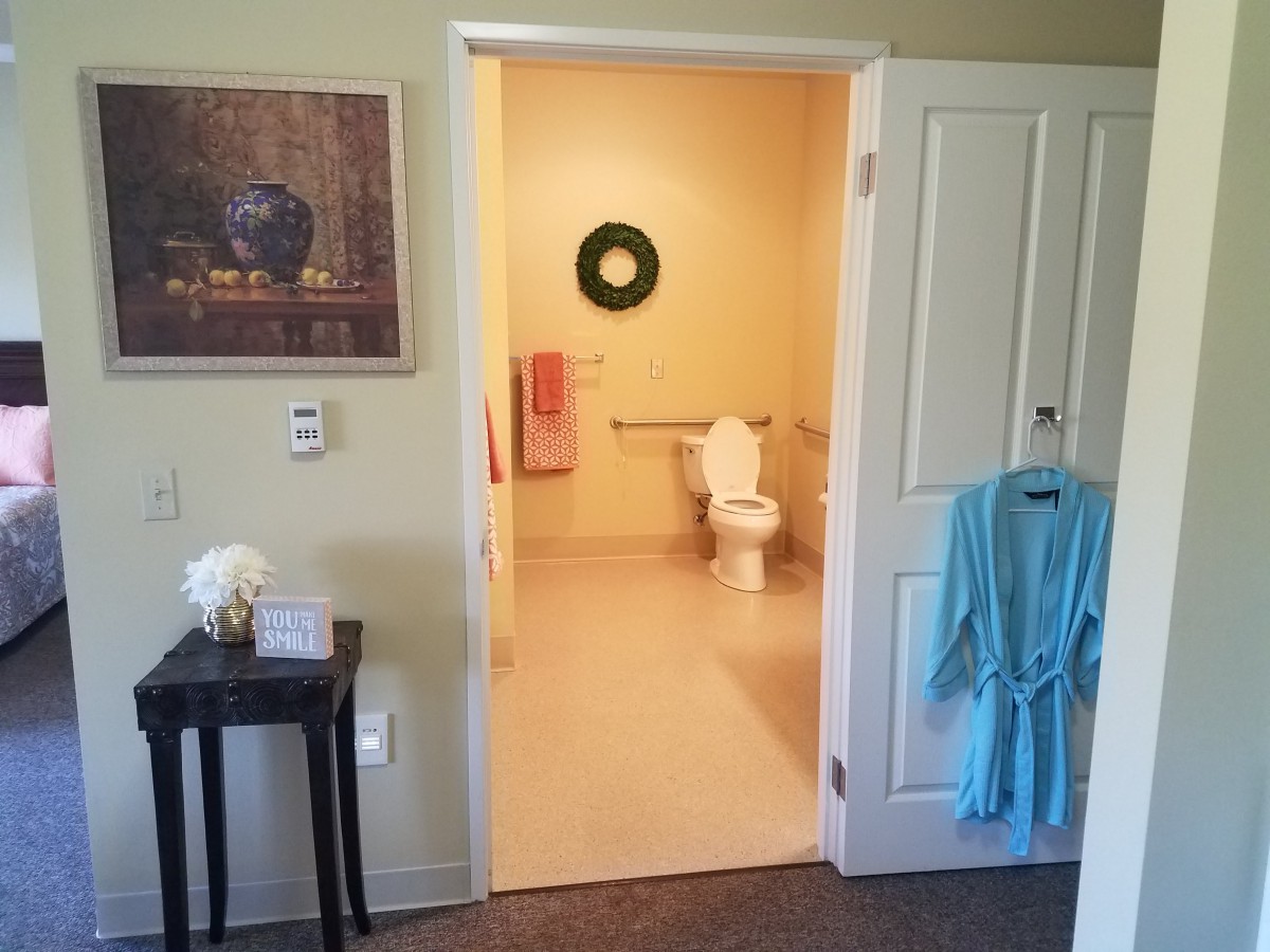 A view of a bathroom through an open doorway, featuring a toilet, towel, and hanging robe.