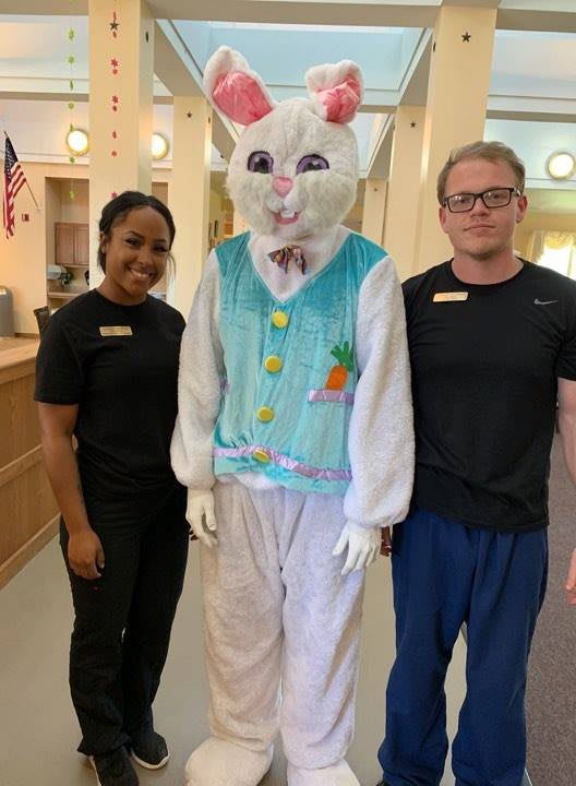 Three people posing indoors, with one person dressed in a bunny costume.