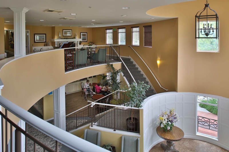 A modern lobby with multiple levels, featuring stairways, seating areas, and decorative plants.