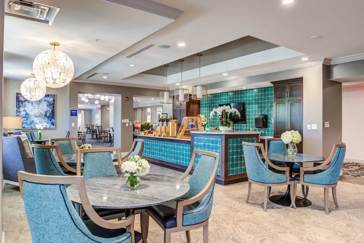 A modern dining area featuring elegant tables and chairs, stylish lighting, and a bar counter with colorful tiles.