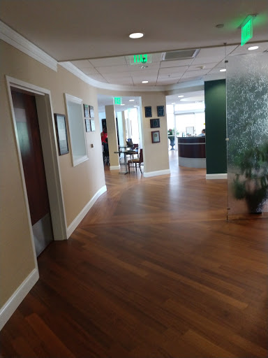 A view of a modern office hallway with wooden flooring and contemporary decor.