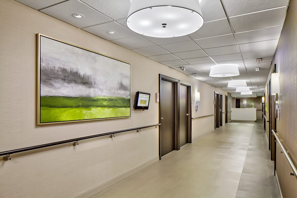 A modern hospital corridor featuring contemporary artwork and bright lighting.