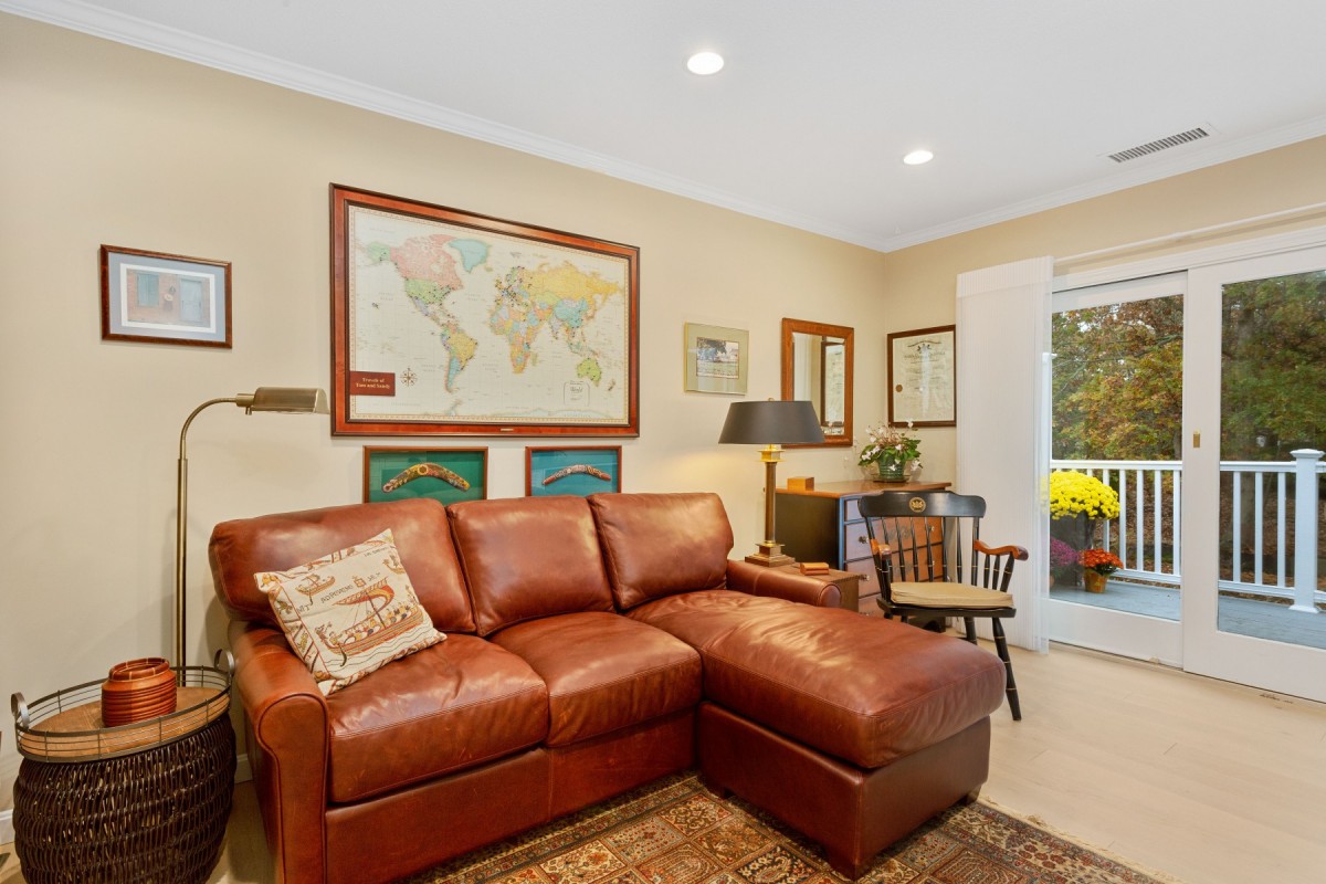 A cozy living room with a leather couch, world map, and various artworks on the walls.