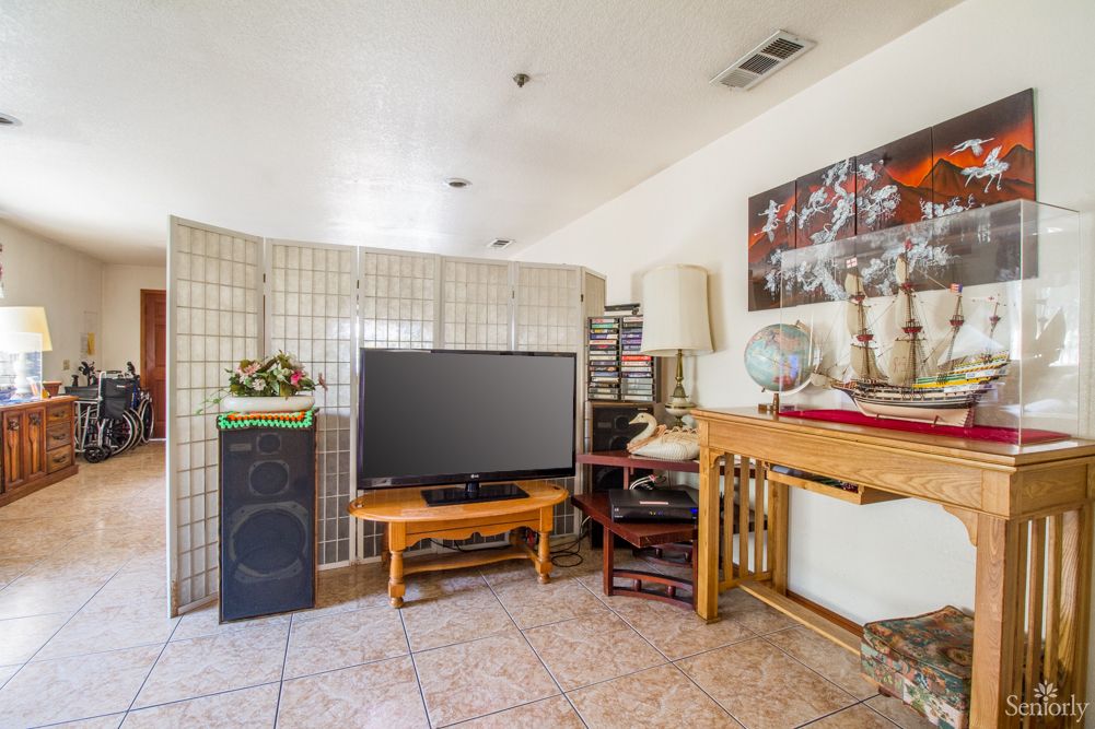 A cozy living room with a television, various furniture pieces, and decorative items.
