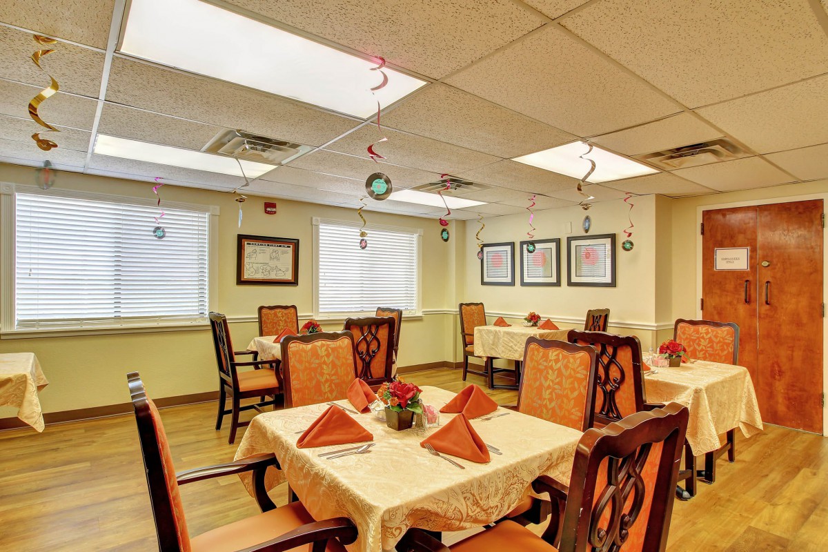 A cozy dining room with tables set for guests, featuring warm lighting and elegant decor.