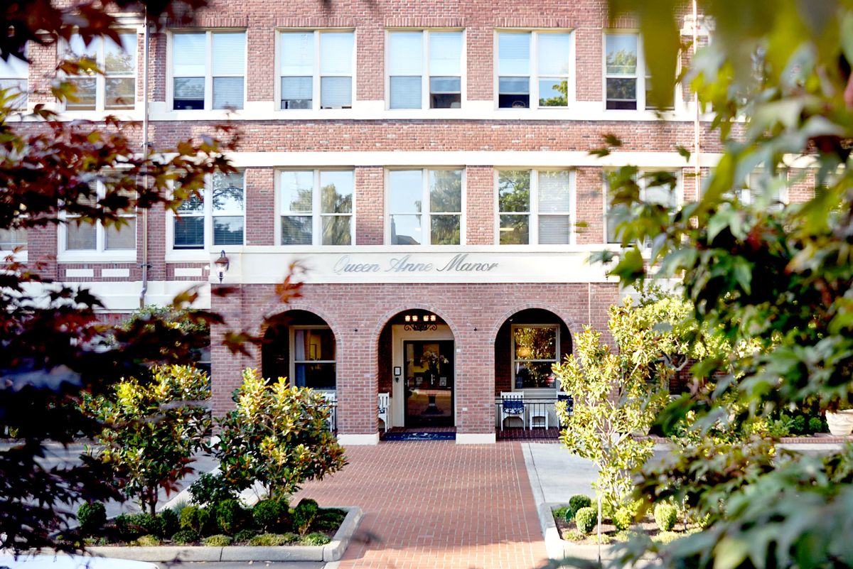 A charming brick building entrance surrounded by trees and greenery.