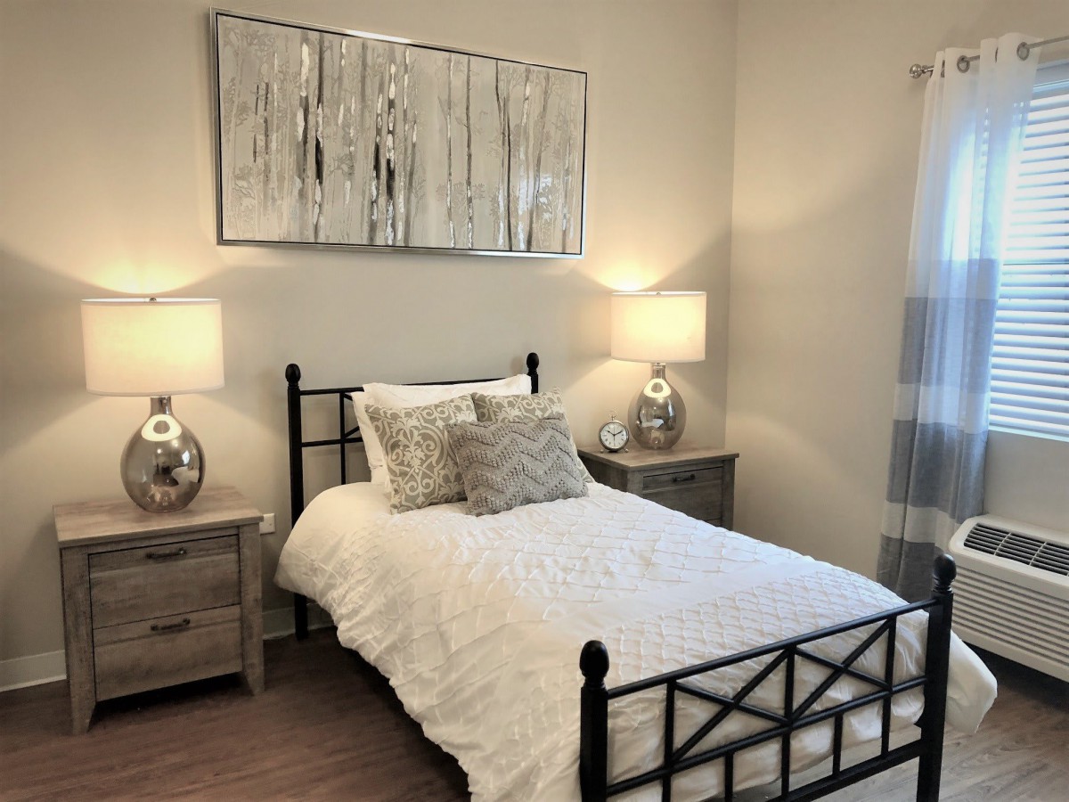 A cozy bedroom with a neatly made bed, bedside tables, and decorative lamps.