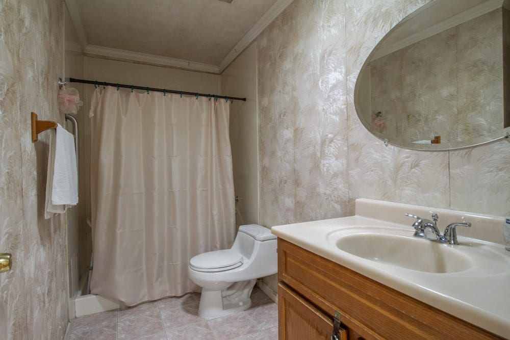A clean and simple bathroom with a toilet, sink, and shower area.