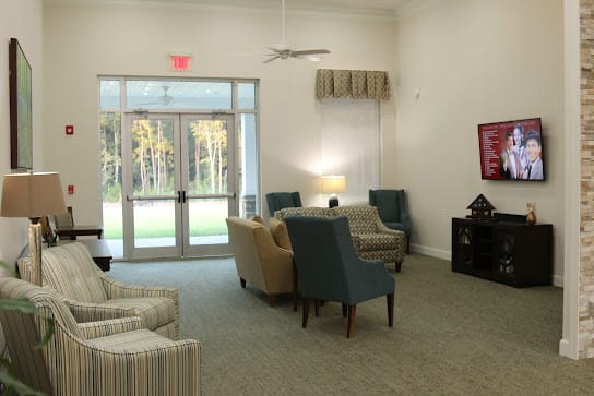 A cozy living room with comfortable seating, soft lighting, and large windows overlooking greenery.