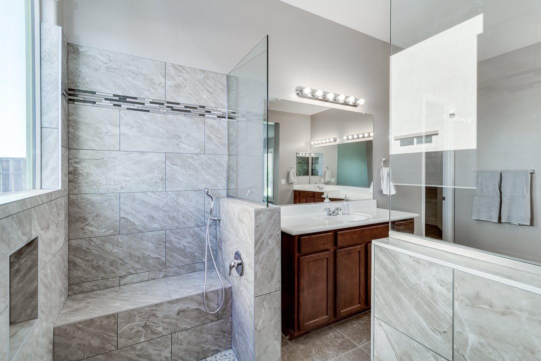 A modern bathroom featuring a glass-enclosed shower and a wooden vanity with a mirror.
