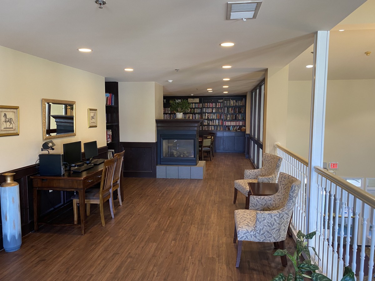 A cozy library corner with bookshelves, a fireplace, and computer workstations.