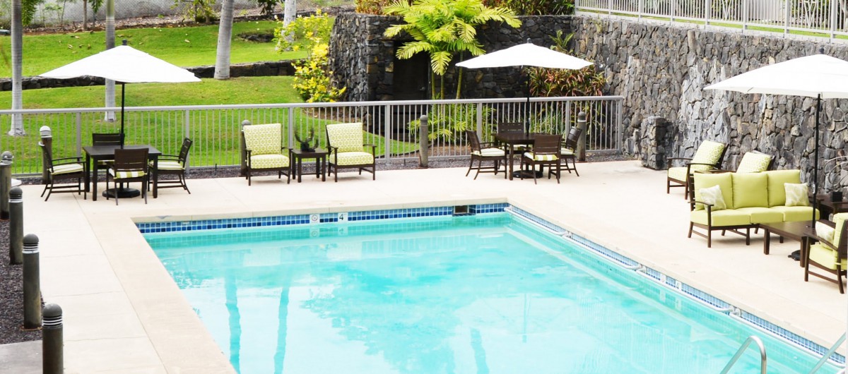 A serene outdoor swimming pool area with patio furniture and tropical landscaping.