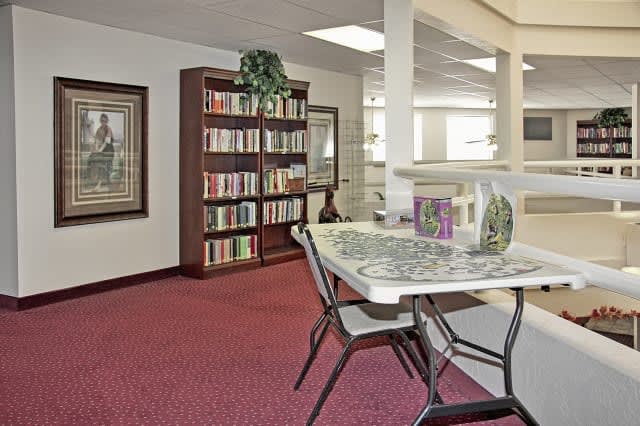 A cozy library corner with a bookshelf, table, and chairs.