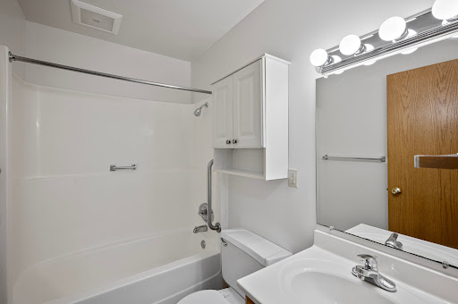A clean, minimalist bathroom featuring a shower, toilet, and sink with modern lighting.