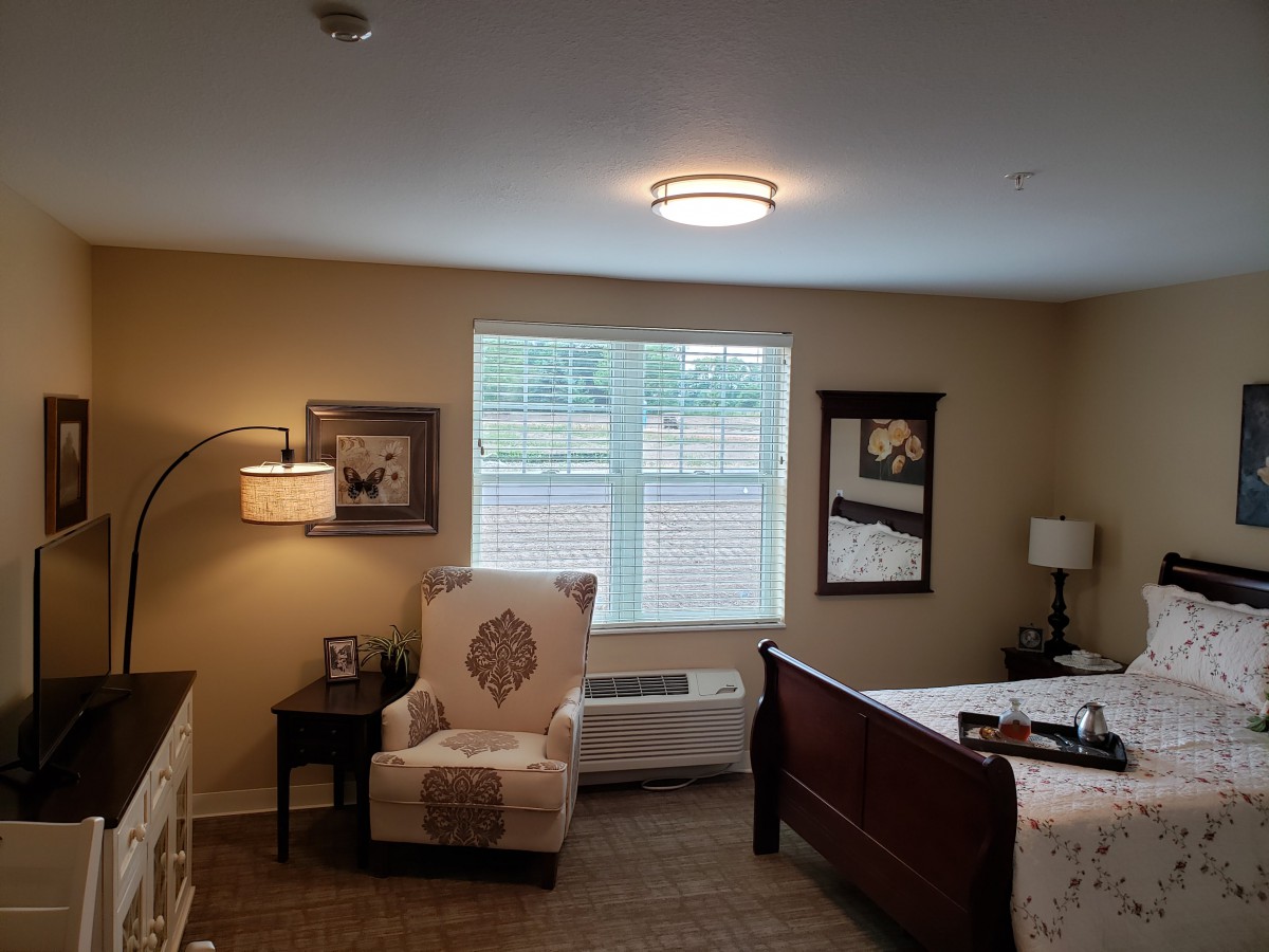 A cozy bedroom with a wooden bed, comfortable chair, and decorative artwork on the walls.
