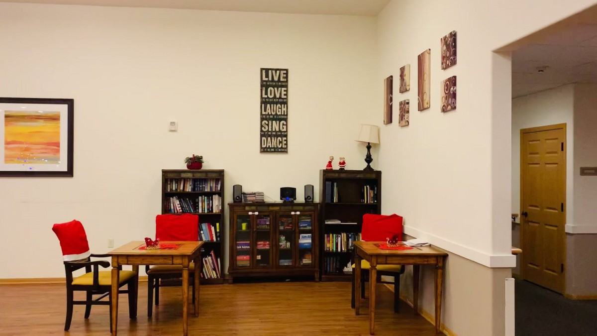 A cozy reading corner with bookshelves, tables, and a lamp.
