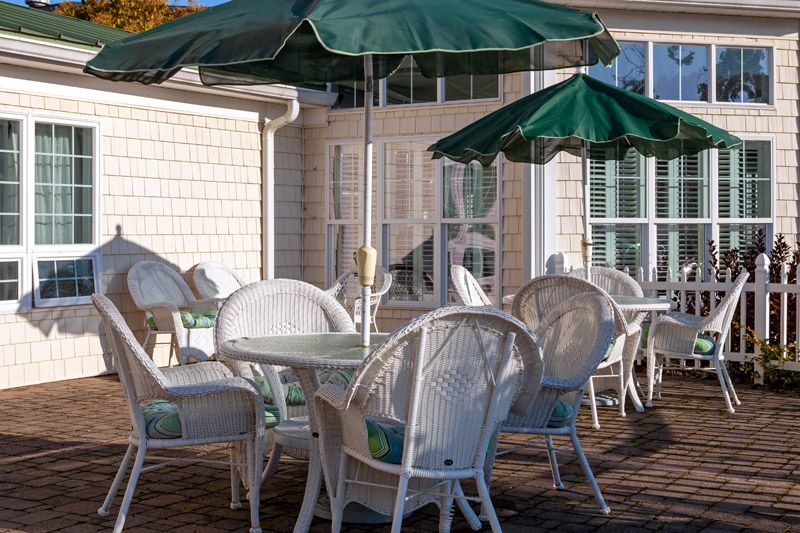 A sunny patio with wicker furniture and green umbrellas.