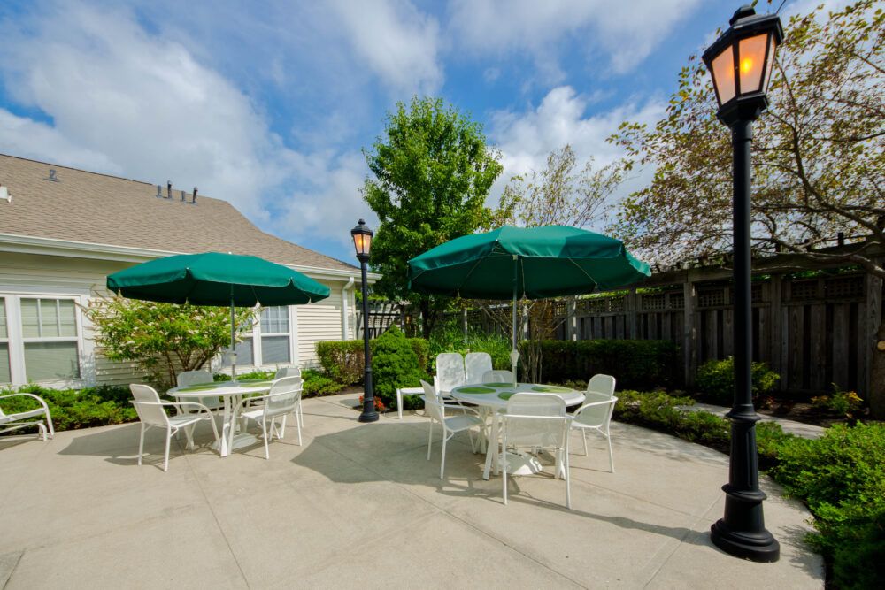 A sunny outdoor patio with tables and chairs under green umbrellas.