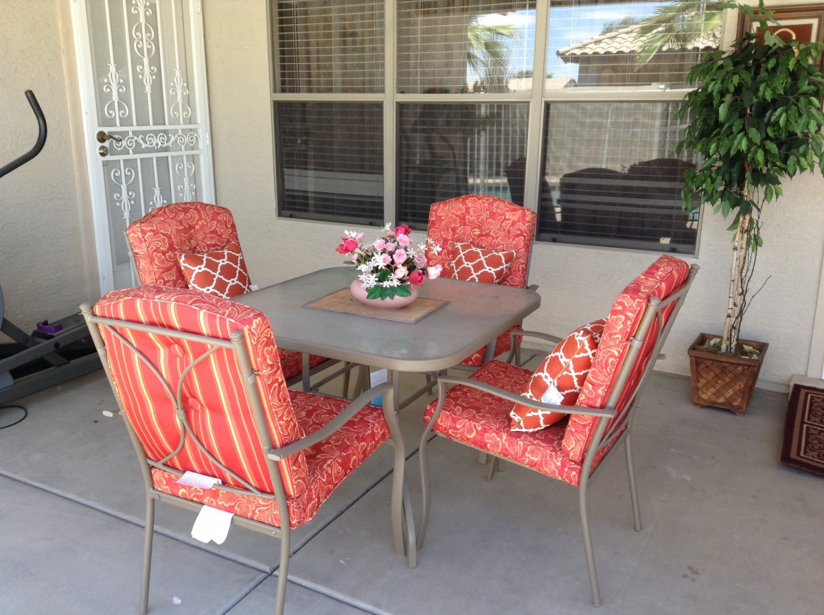 A cozy outdoor patio setup with a table and four cushioned chairs.