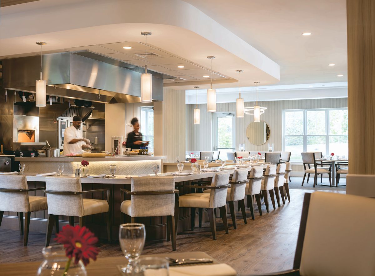 A modern restaurant interior featuring an open kitchen and elegant dining area.