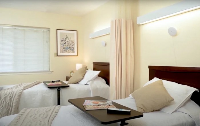 A hospital room with two beds, medical equipment, and soft lighting.