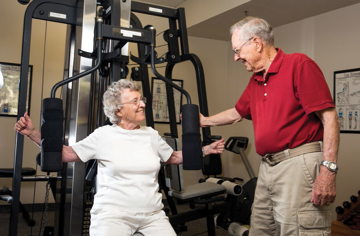 Two seniors enjoying a workout session on strength training equipment.