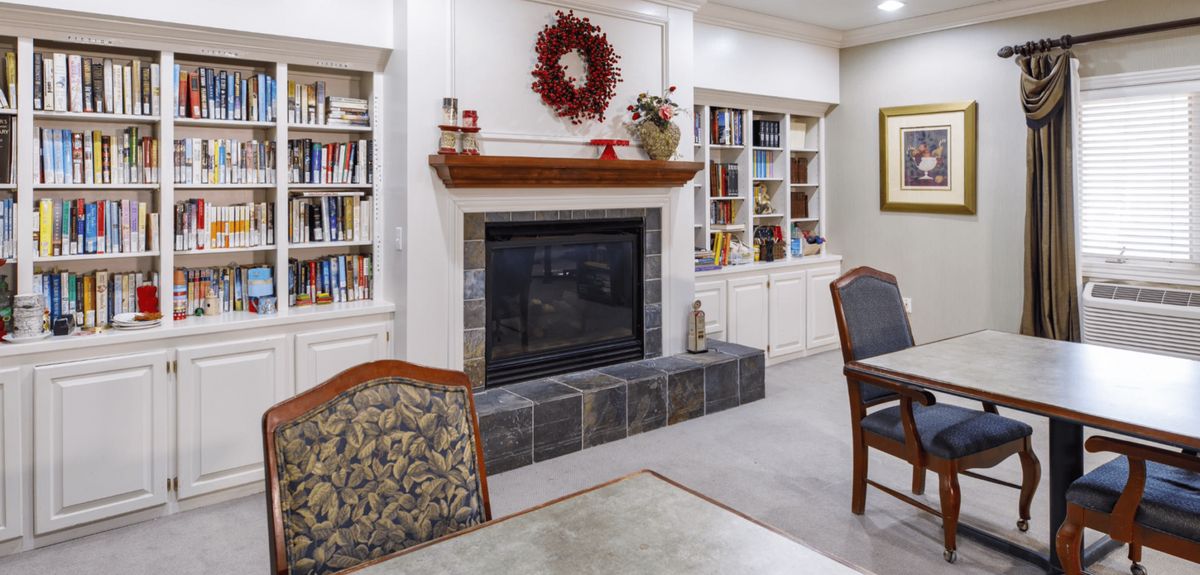 A cozy living room featuring a fireplace surrounded by built-in bookshelves and decorated with a wreath.