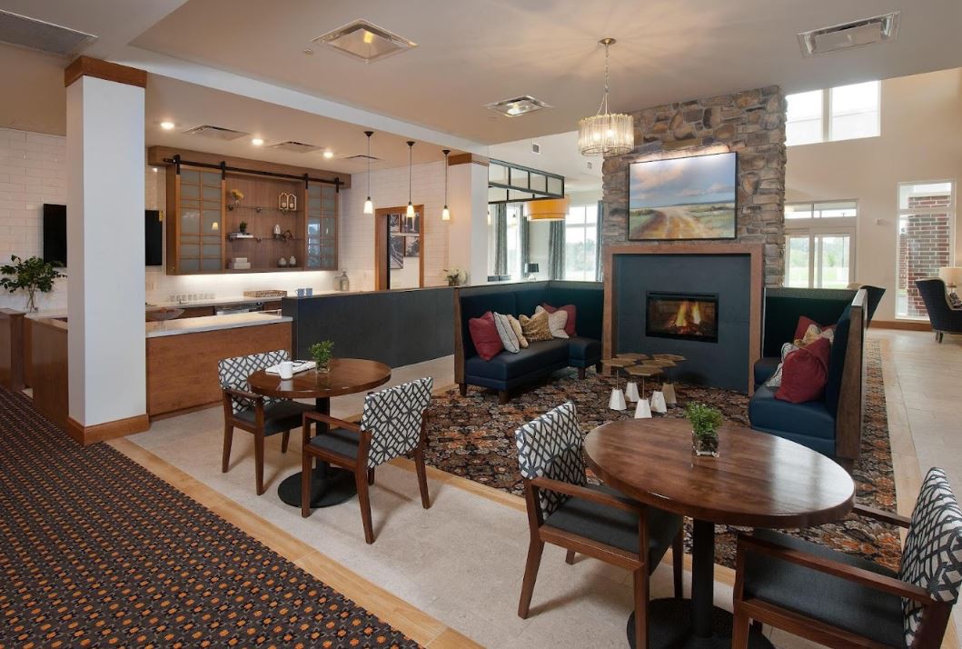 A modern and cozy seating area with a fireplace, featuring comfortable furniture and wooden tables.